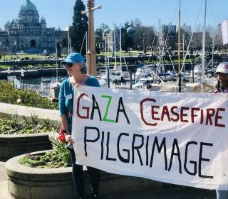 People carry a large banner for the Gaza Ceasefire Pilgrimage in Victoria, BC.