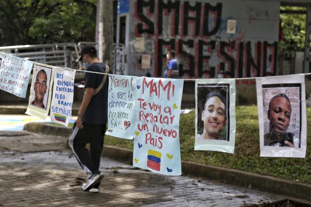 A man walks past a line of photos of people who have been killed during the Colombian protests of April-May 2021
