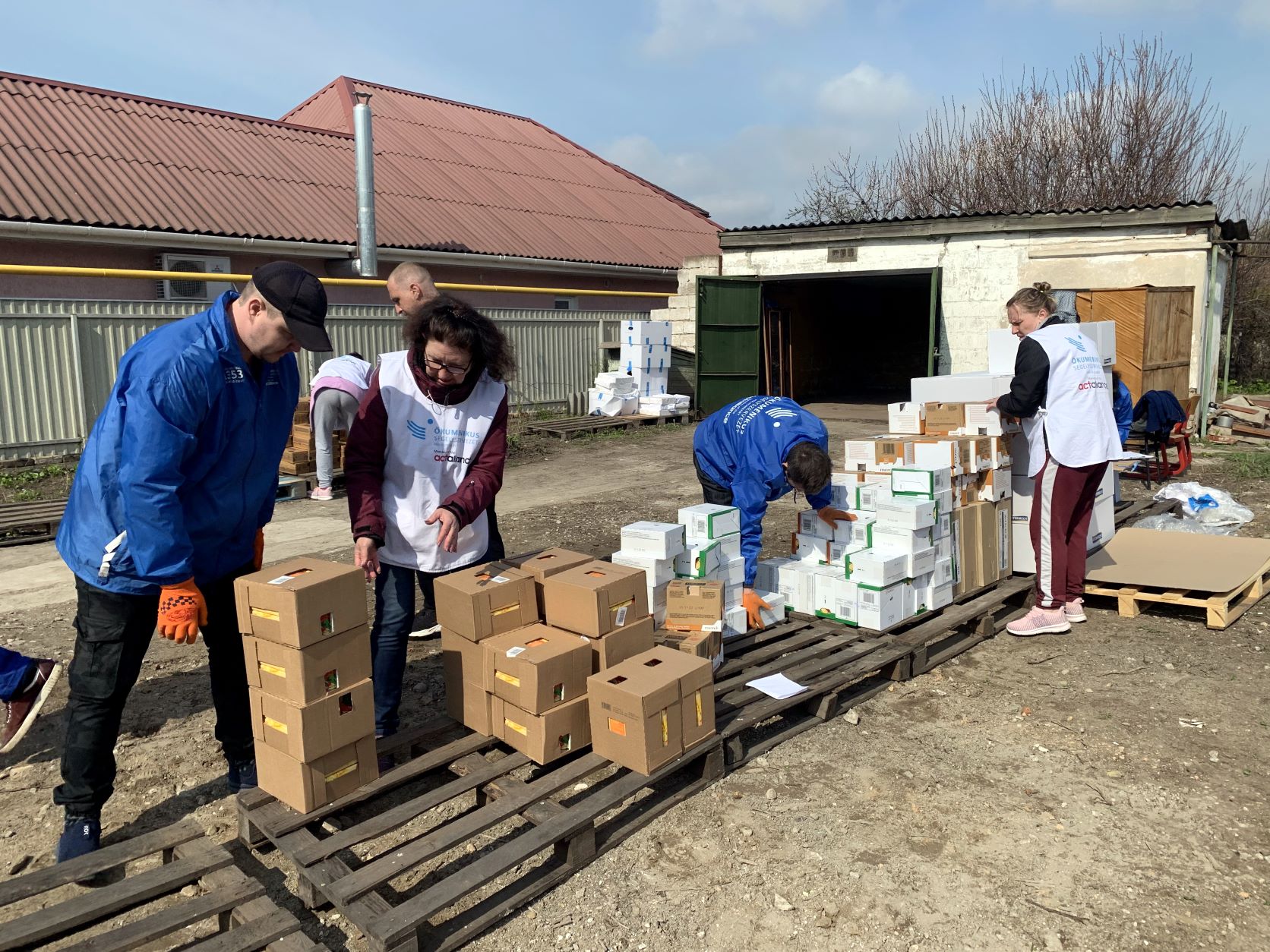 Aid workers load boxes of relief supplies onto pallets outdoors.