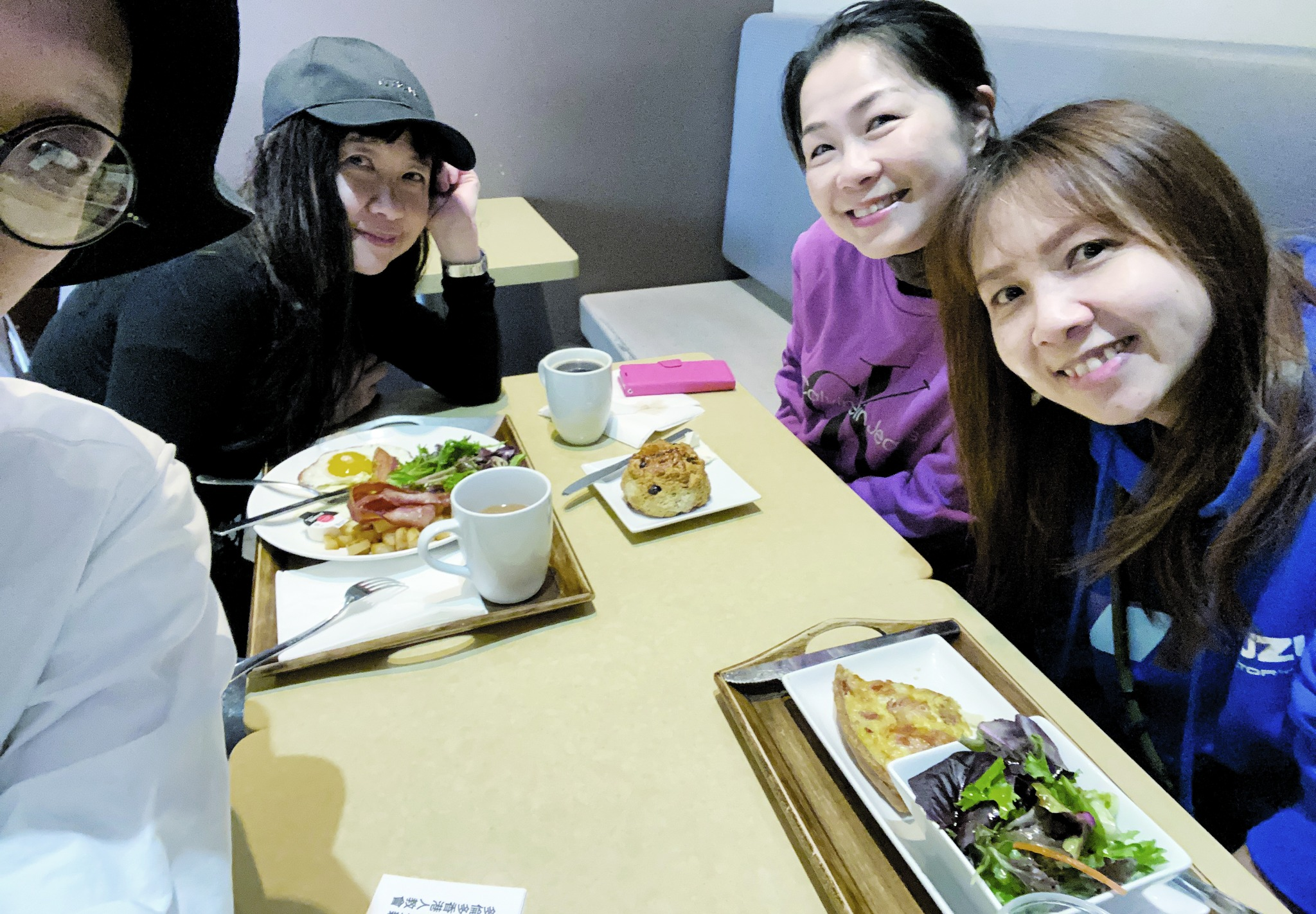 Four young people smiling for a selfie around a table with food
