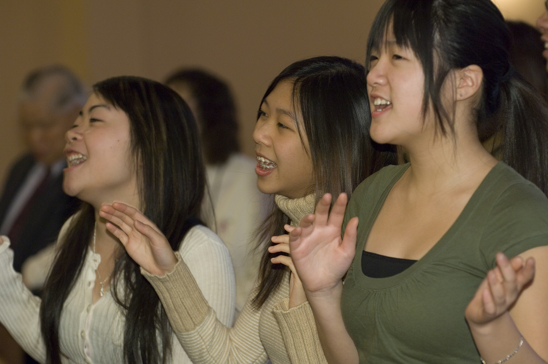 A group of Asian descent people singing and raising hands