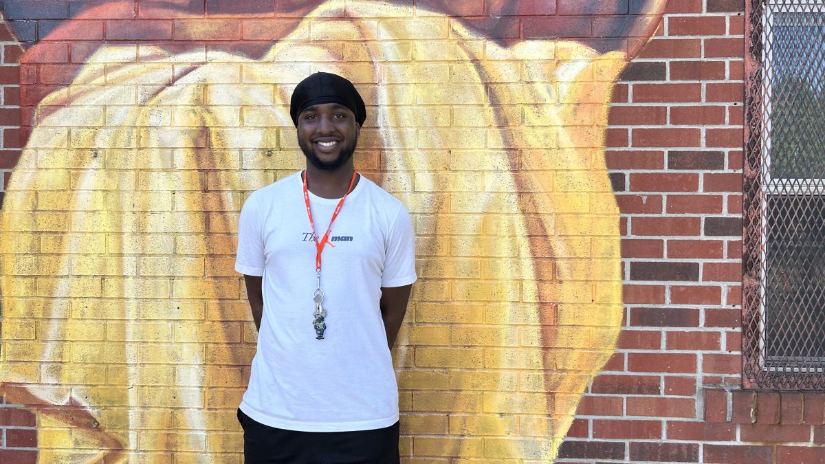 Cyris stands next to a mural at the Beasley Community Centre