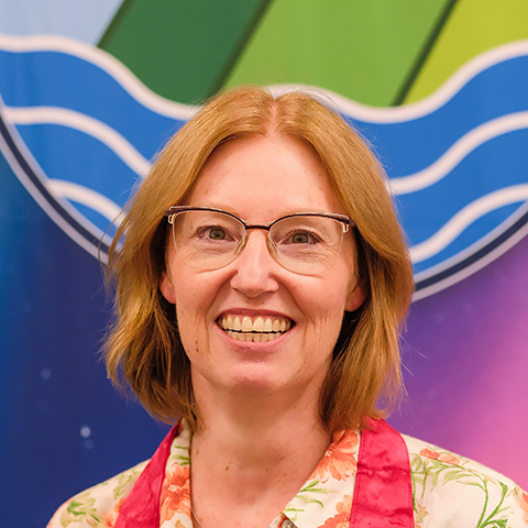 Rev. Kimberly smiling widely in front of a banner with the GC45 logo