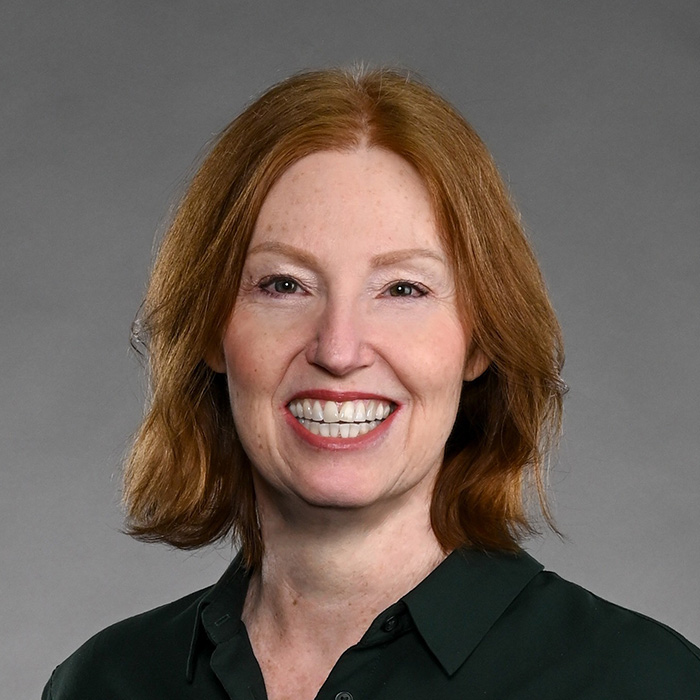 Red head Kimberly smiling widely, wearing red lipstick and a black top