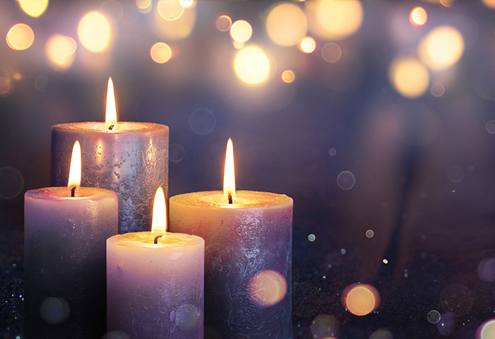 Four candles burning in front of a glittering backgound