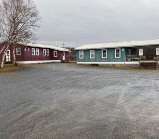 Two one-storey buildings at the end of a gravel road