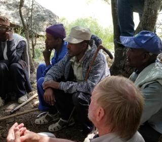 A group of men in Ethiopia sitting on the ground listening to someone