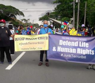 People on street hold up banners protesting human rights abuses in the Philippines