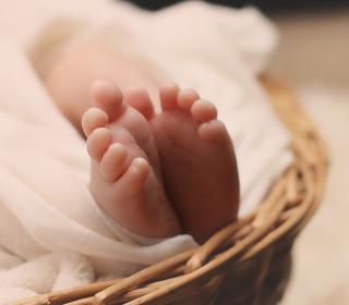 A White baby's feet emerge from the blanket they're wrapped in