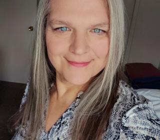 A selfie of Rev. Cindy Bourgeois, a woman with blue eyes and silver hair, trailed with dark brown highlights at the ends. 