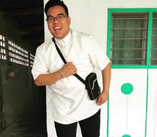Klaus Simon Bondoc, a young Fillipino man with a brilliant smile, appears to be exclaiming while dressed in a white alb.