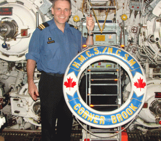 Lieutenant Commander (Padre) Earl Klotz, in uniform, standing inside a submarine.