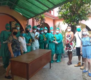 15 health workers and others wearing masks stand in the courtyard of a building in Cuba.
