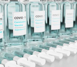 A row of small vaccine bottles with labels saying COVID-19 coronavirus vaccine