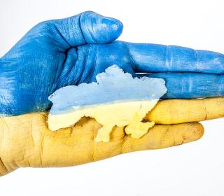 Ukraine flag overlaid on hand with outline of country