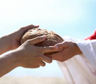 Hands that look like Jesus' hold out bread to another person's hands.