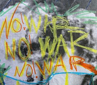 The words No! War are painted three times in yellow and orange on a wall.