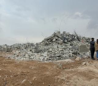 A huge pile of concrete rubble mark all that is left of the K. family home after demolition. Groups of people are seen standing around the pile, including Ecumenical Accompaniers.