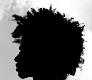 A silhouette head shot photo of Jonisha Lewinson, a young Black woman with free-flowing hair.