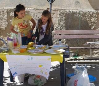Children selling lemonade at a homemade stand outside in the summer.