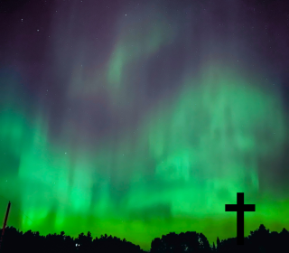 A cross silhouetted against the Northern Lights.