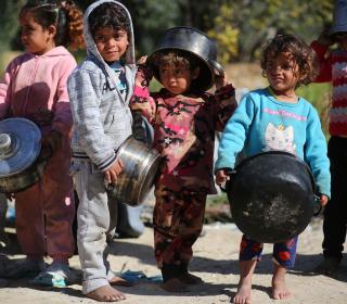 Row of very young Palestinian children holding cooking pots