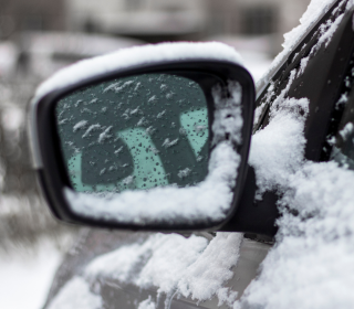 Side mirror on car covered in snow