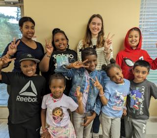 Group of smiling children make the peace sign with their hands