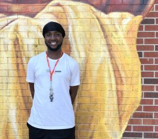 Cyris stands next to a mural at the Beasley Community Centre