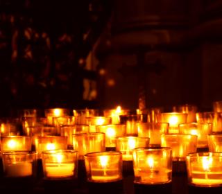 Many lighted votive candles in the dark