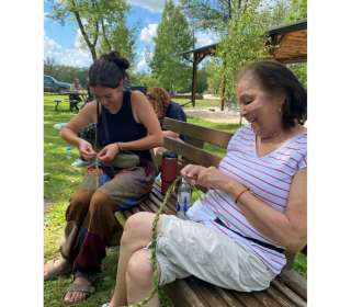 Two women braid sweetgrass at the Sandy-Saulteaux Spiritual Centre 