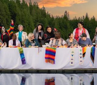 "A Place at the Table" - an iconic image of 12 diverse disciples at a long table, positioned on a dock in a mountain lake.