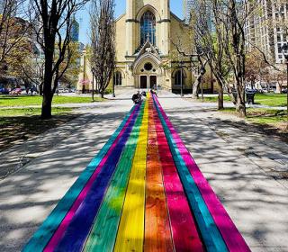 A rainbow coloured 100 foot table in front of the historic Metropolitan United Church Toronto