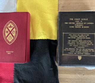 The United Church Mohawk Bible lies on a black, yellow, white, and red flag, next to the former Union Bible.