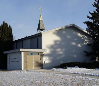 A small white church in front of a snowy lawn.