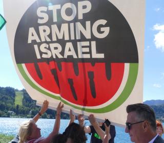 A small group of people holding up a sign that reads "Stop Arming Israel"