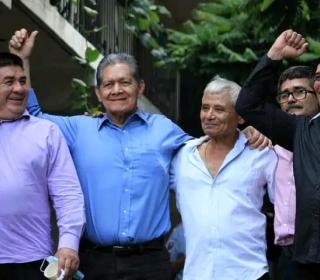 Five Salvadoran men embrace and raise fists in a celebratory gesture