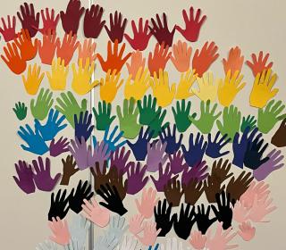 An artwork made of many handprints in rainbows on a wall