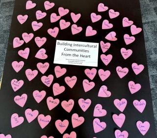 A poster filled with pink hearts, each with a name written on them