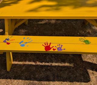 A yellow picnic table with painted handprints on it 
