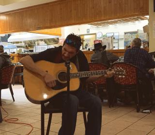 A man plays guitar in a community centre