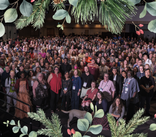 A large group photo with a Christmas wreath overlaid
