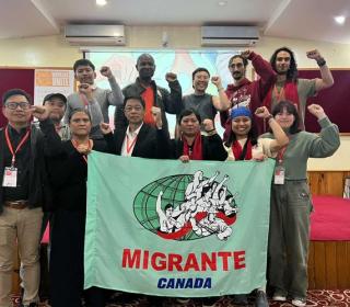 A group of people with fists raised and a sign that reads "Migrante Canada"