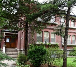 A large red-brick house behind trees