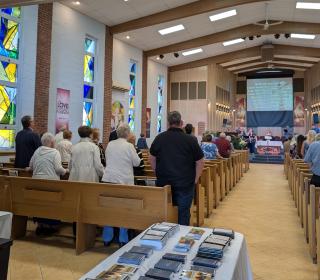 A photo of a church interior full of standing members