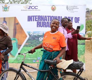 A smiling African woman poses with a bicycle