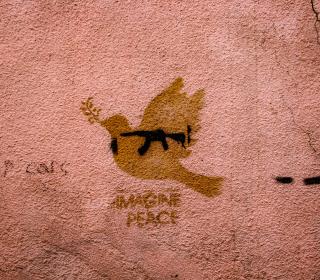 Graffiti on a wall shows a peace dove with a gun over-imposed.