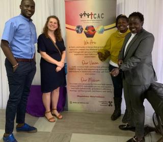 A group of four people smiling in front of a banner with info on CAC