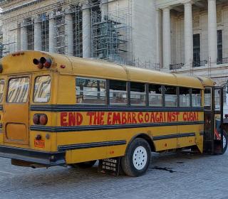 A school bus in Havana with graffiti painted on it that says "End the embargo against Cuba!"
