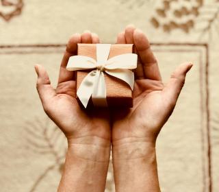 Someone holding a small wrapped gift in their hands